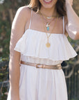 Woman wearing a white dress with gold jewelry outdoors