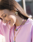 Woman wearing a pink top and colorful jewelry outdoors