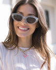Woman wearing sunglasses and Chunky Wheat Chain Necklace with pink horseshoe charm with a blurred background
