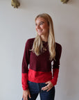 Woman wearing a red and burgundy sweater with a white background