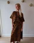Woman wearing a tiger print set standing in a room with white walls and wooden flooring.