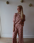 Person wearing a pink floral outfit standing in a room with white walls and wooden flooring.