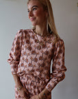 Woman wearing a floral sweatshirt with a neutral background
