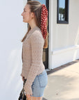 Woman with a red polka dot headscarf standing outside a building
