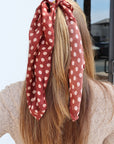 Person with long hair wearing a red polka dot headscarf