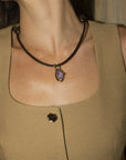 model wearing the kostas necklace with a tan top and a dim background