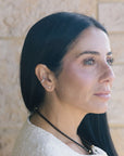 Woman with long dark hair wearing a necklace against a stone wall background wearing Make Your Move Pave Spade Post