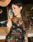 Woman in a floral dress holding a glass of champagne in a bar setting