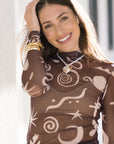 Woman wearing a brown patterned top and Cape Necklace White with a blurred background