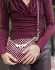 Person holding a pink and raisin checkered handbag with gold accents