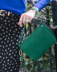 Green handbag with Cameo Fob held by a person wearing a blue sweater and polka dot skirt.
