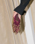 Hand holding a purple beaded clutch against a neutral background
