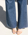 Close-up of blue jeans and brown sandals on a light background