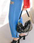 Person holding a black studded handbag with a blurred background