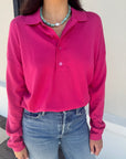 Person wearing a bright pink long-sleeve polo shirt and blue jeans, close up, top tucked in