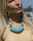 Woman wearing a turquoise necklace with a blurred outdoor background