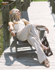 Woman sitting on a wooden deck wearing a white outfit with a colorful headscarf.