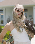 Woman in a white top and sunglasses standing outdoors.