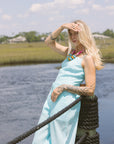 Woman in a blue matching set standing by a body of water with a rope railing.