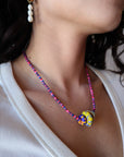 Close-up of a colorful beaded necklace on a person wearing a white top.