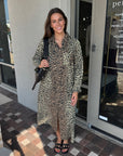 Woman in a leopard print dress standing outside a store