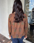 Person wearing a patterned shirt standing in front of a store entrance, back