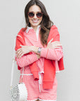 Woman wearing a red and white striped outfit with sunglasses against a gray background