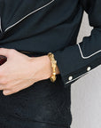 Person wearing a gold bracelet with a black outfit