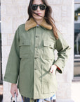 Woman wearing The Quilted Liner Parka green coat with a fur-lined hood outdoors front view