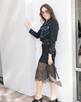 faye lace skirt on a model with a black western top, leather belt, black heels, on a white wall, side view