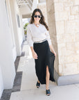 Fizz long drape skirt on a model with a cream wrap sweater and black heels front view