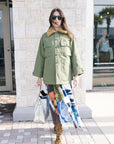 The Quilted Liner Parka front view button up on model in front of brick with leopard shoes and silver bag