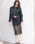 faye lace skirt on a model with a black western top, leather belt, black heels, on a white wall, front view