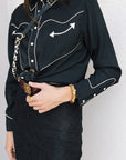 model wearing woman wearing the western shirt with black outfit with white accents and sunglasses against a plain background zoomed in
