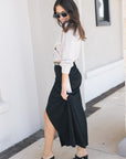 Fizz long drape skirt on a model with a cream wrap sweater and black heels side view