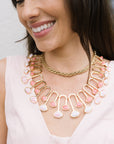 Woman wearing a gold and pink necklace with a blurred background