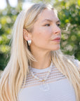 Woman with long blonde hair wearing a necklace and Leona Hoops Silver outdoors