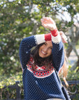 Woman wearing a colorful sweater with a patterned design outdoors.