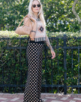 Woman wearing Cleo Chacana Top with geometric patterns and a black polka dot pants outdoors.