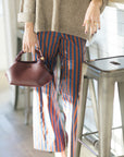 Person wearing striped pants and holding a brown handbag, close up