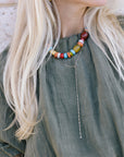 Close-up of a person wearing a colorful beaded necklace and Ace Lariat