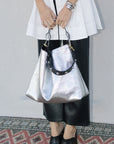 Person holding Istrala Silver Shopper Bag with Clare V Stud strap with a plain background