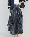 Person wearing a black polka dot skirt with a plain background