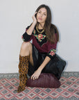 Model crouching with vino bag and cheetah boots