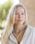 Woman with long blonde hair wearing a striped shirt and necklace outdoors