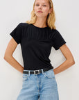 Woman wearing a black top and blue jeans against a white background front view