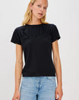 Woman wearing a black ruffled t-shirt and blue jeans on a white background front view