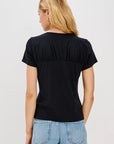 Person wearing a black t-shirt and light blue jeans on a plain background back view