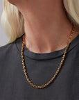 Gold chain necklace worn by a person with a neutral background