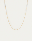 Gold chain necklace on a light gray background